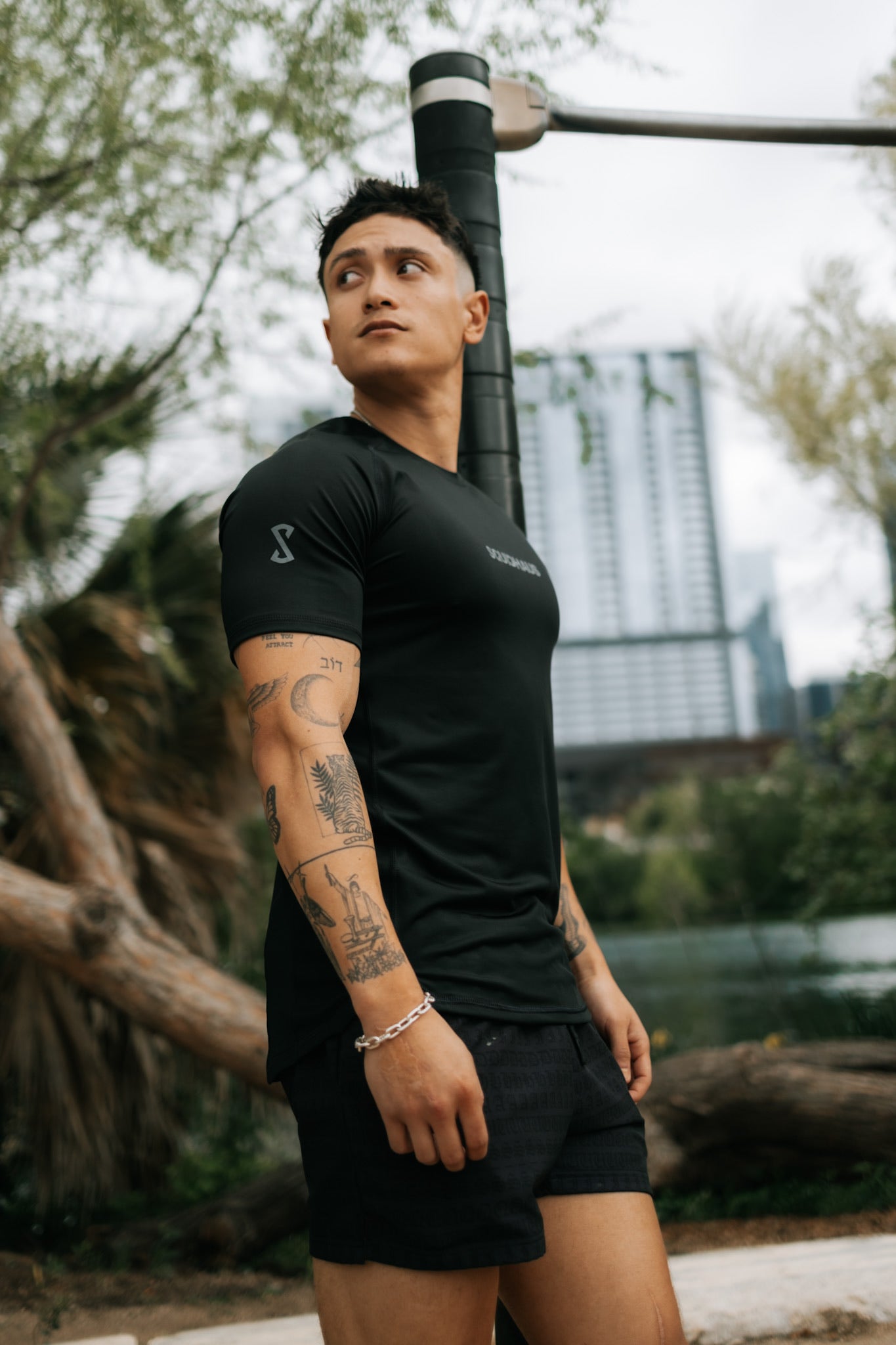 A model wearing the black Pro-tech V1 Athletic Fitted Short Sleeve T-Shirt and 4 inch inseam mesh shorts in black, both by SquidHaus